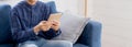 Young attractive asian man resting using browsing tablet computer on sofa at home. Royalty Free Stock Photo