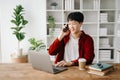 Young attractive Asian man smiling thinking planning writing in notebook, tablet and laptop working from home at home office Royalty Free Stock Photo