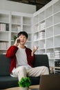 Young attractive Asian man smiling thinking planning writing in notebook, tablet and laptop working from home at home office Royalty Free Stock Photo