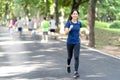 Young attractive asian runner woman running in urban public nature park in city