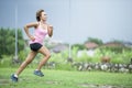 Young attractive Asian sport runner woman running in the jungle smiling happy in training workout on herb background in fitness Royalty Free Stock Photo