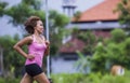 Young attractive Asian sport runner woman running in the jungle smiling happy in training workout on herb background in fitness Royalty Free Stock Photo