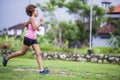 Young attractive Asian sport runner woman running in the jungle smiling happy in training workout on herb background in fitness Royalty Free Stock Photo