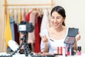 Young attractive asian woman beauty blogger or vlogger smiling looking at camera and talking on video shooting while make up.