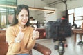 Young attractive asian woman blogger or vlogger looking at camera and talking on video shooting at cafe coffee shop. Royalty Free Stock Photo