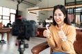 Young attractive asian woman blogger or vlogger looking at camera and talking on video shooting at cafe coffee shop. Social media Royalty Free Stock Photo