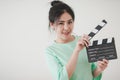 Young Asian woman playing clapperboard with positive emotion