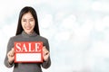 Young attractive asian woman holding sale signboard card showing for price tag looking at camera Royalty Free Stock Photo