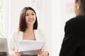 A young attractive asian woman is interviewing for a job. Her interviewers are diverse.