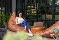 young attractive asian woman taking note and working over laptop in resting zone at the hotel during travel on vacation Royalty Free Stock Photo