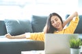Young attractive asian woman work at home wearing casual yellow shirt in living room with sofa couch, table, pillow and laptop Royalty Free Stock Photo
