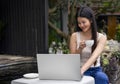 young attractive asian woman working over laptop while take a break in the resort garden on summer vacation Royalty Free Stock Photo