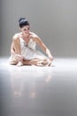 Young attractive ballerina sitting on the floor working with her pointed ballet shoes
