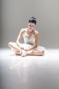 Young attractive ballerina sitting on the floor working with her pointed ballet shoes
