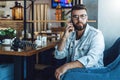 Young attractive bearded hipster man in trendy glasses sits in a cafe during lunch, talking on a cell phone. Lifestyle Royalty Free Stock Photo