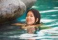Young attractive and beautiful Asian Korean woman relaxing happy at tropical beach luxury resort swimming at jungle infinity pool Royalty Free Stock Photo