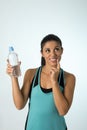 Young attractive and beautiful Latin sport woman holding water of bottle thinking if drinking more