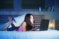 Young attractive and beautiful 20s Asian Chinese woman lying on bed at night using internet in laptop computer watching on line mo Royalty Free Stock Photo