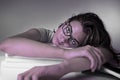 Young attractive and beautiful tired student girl leaning on school books pile tired and exhausted studying Royalty Free Stock Photo