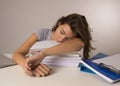 Young attractive and beautiful tired student girl leaning on school books pile sleeping tired and exhausted after studying Royalty Free Stock Photo