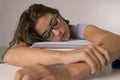 Young attractive and beautiful tired student girl leaning on school books pile sleeping tired and exhausted after studying Royalty Free Stock Photo