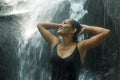 Young attractive and blissful Asian Indonesian woman overwhelmed by the beauty of natural waterfall in tropical jungle enjoying Royalty Free Stock Photo