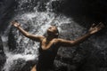 Young attractive and blissful Asian Indonesian woman overwhelmed by the beauty of natural waterfall in tropical jungle enjoying Royalty Free Stock Photo