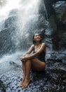 Young attractive and blissful Asian Indonesian woman overwhelmed by the beauty of natural waterfall in tropical jungle enjoying Royalty Free Stock Photo