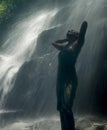 Young attractive and blissful Asian Indonesian woman overwhelmed by the beauty and purity of natural waterfall in tropical jungle Royalty Free Stock Photo