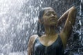 Young attractive and blissful Asian Indonesian woman overwhelmed by the beauty and purity of natural waterfall in tropical jungle Royalty Free Stock Photo