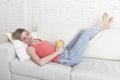 Young attractive blond hair woman holding cup of coffee lying on sofa couch at home living room sleeping relaxed Royalty Free Stock Photo