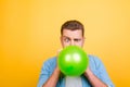 Young attractive blond man tired to blow up balloons new year pa