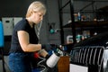 Young attractive blond woman, worker of car detailing service, removing dust from car radiator grille using aero gun for Royalty Free Stock Photo