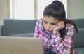 Young attractive and bored latin woman on her 30s working at home living room sitting on couch with laptop computer in stress look Royalty Free Stock Photo