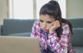 Young attractive and bored latin woman on her 30s working at home living room sitting on couch with laptop computer in stress look Royalty Free Stock Photo