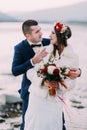 Young attractive bridal couple posing on pebble riverside with forest hills as background Royalty Free Stock Photo