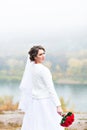 Young attractive bride with the bouquet of red roses over snowy Christmas background Royalty Free Stock Photo