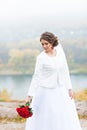 Young attractive bride with the bouquet of red roses over snowy Christmas background Royalty Free Stock Photo