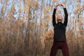 Young attractive brunet slim woman in sportswear doing stretching exercise for hand in autumn forest. Warm up before Royalty Free Stock Photo