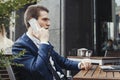 Young attractive brunette businessman talking by mobile phone in cafe. Royalty Free Stock Photo