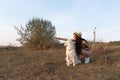 Young attractive brunette girl in beige dress and hat crouched near the samoyed puppy and pointing at left side Royalty Free Stock Photo