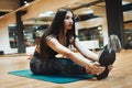 Young attractive brunette girl enlacing her sport shoes after practicing workout and crossfit training on blue yoga mat. Royalty Free Stock Photo