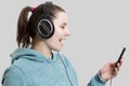 Young attractive brunette girl in headphones with player. Beautiful woman listening to music with headphones isolated on gray Royalty Free Stock Photo