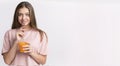 Young attractive brunette girl holding takeaway bottle with detox orange drink Royalty Free Stock Photo