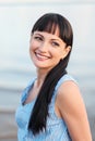 A young attractive brunette woman, in a blue dress, walks along the seashore. Portrait of a smiling woman on vacation Royalty Free Stock Photo