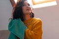 Close up of attractive brunette woman in yellow sweater drying curly hair with blue towel. Curly method of hair care.