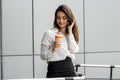 Young attractive business Lady holding a cup of coffee and talking on the phone Royalty Free Stock Photo