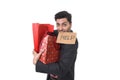 Young attractive business man in stress holding lot of shopping bags and showing help sign on his mouth looking tired bored and wo Royalty Free Stock Photo