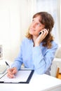 Young attractive business woman copying data on paper while phoning