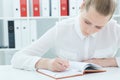 Young attractive business woman making notes at office workplace. Royalty Free Stock Photo